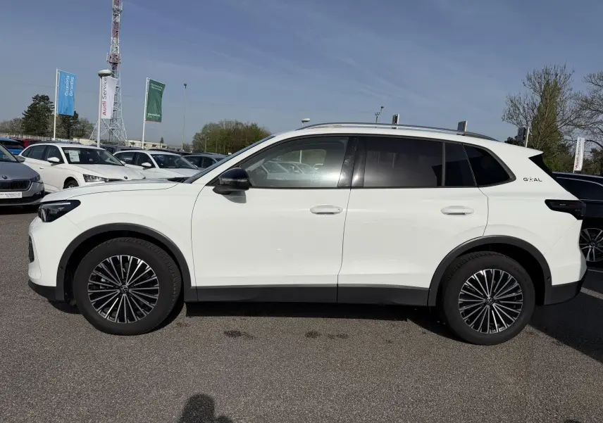 Vue de profil côté gauche d'un Volkswagen Tiguan blanc avec jantes alliage noir brillant et vitres teintées.