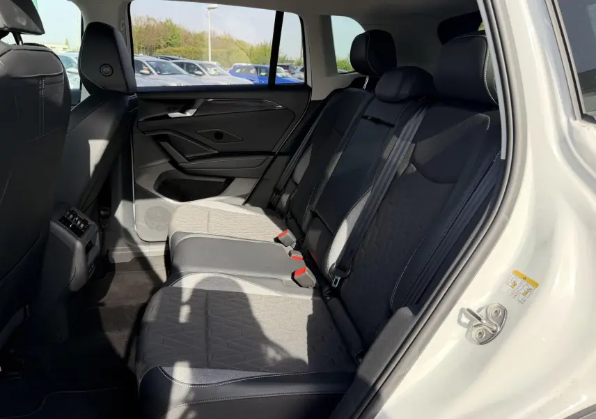 Vue intérieure côté droit des sièges arrière noirs et gris du Volkswagen Tiguan blanc avec porte ouverte au soleil.