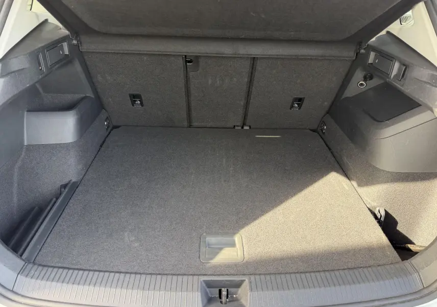 Coffre ouvert du Volkswagen Tiguan blanc, vue intérieure montrant un espace de chargement propre et bien agencé.