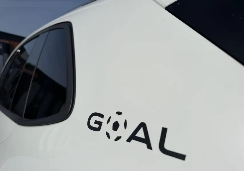 Gros plan sur la partie arrière gauche blanche du Volkswagen Tiguan avec l’inscription noire "GOAL" stylisée ballon de foot.