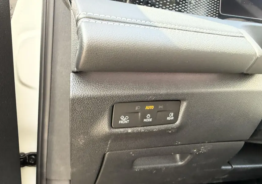 Détail du tableau de bord côté gauche d’un Volkswagen Tiguan blanc, avec commandes d’éclairage en mode automatique.