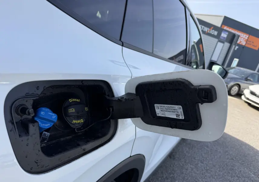 Vue rapprochée de la trappe à carburant côté gauche d’un Volkswagen Tiguan blanc avec bouchon diesel visible.