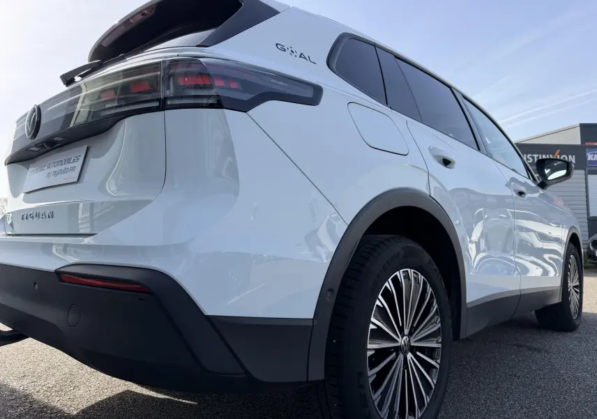 Vue 3/4 arrière droite du Volkswagen Tiguan blanc avec jantes alliage noir brillant et feux arrière LED sombres.