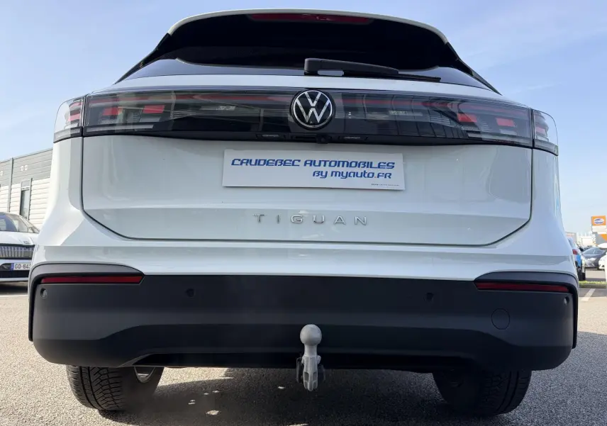 Vue arrière du Volkswagen Tiguan blanc 2025 avec attelage rabattable et feux arrière LED noirs.