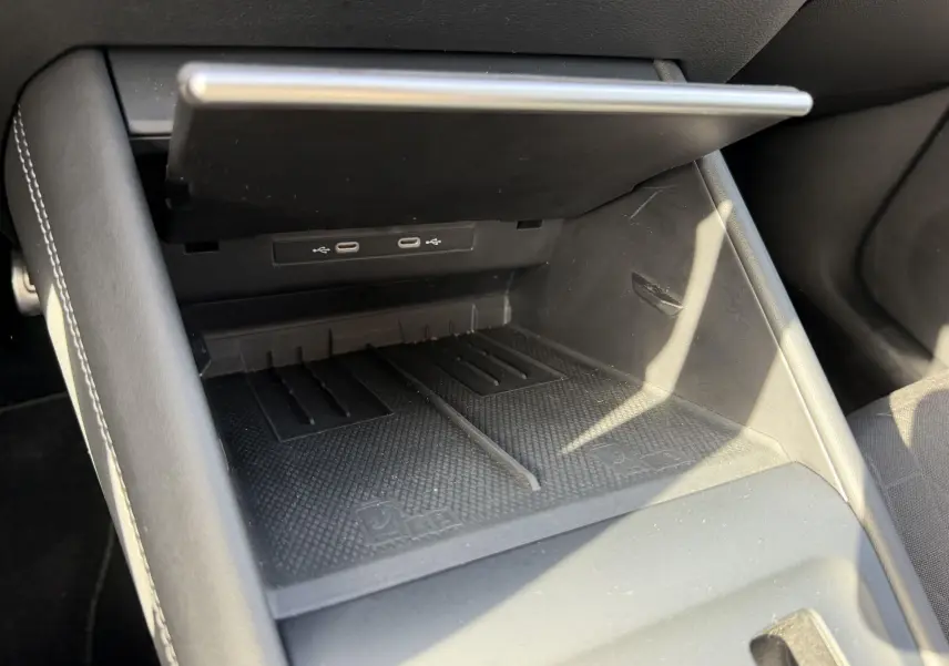 Gros plan sur la console centrale ouverte du Volkswagen Tiguan 2025, montrant les ports USB et l'espace de rangement noir.