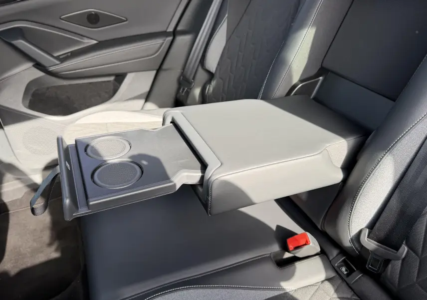 Vue intérieure du côté droit des sièges arrière noirs du Volkswagen Tiguan avec accoudoir central déployé et porte-gobelets visible.