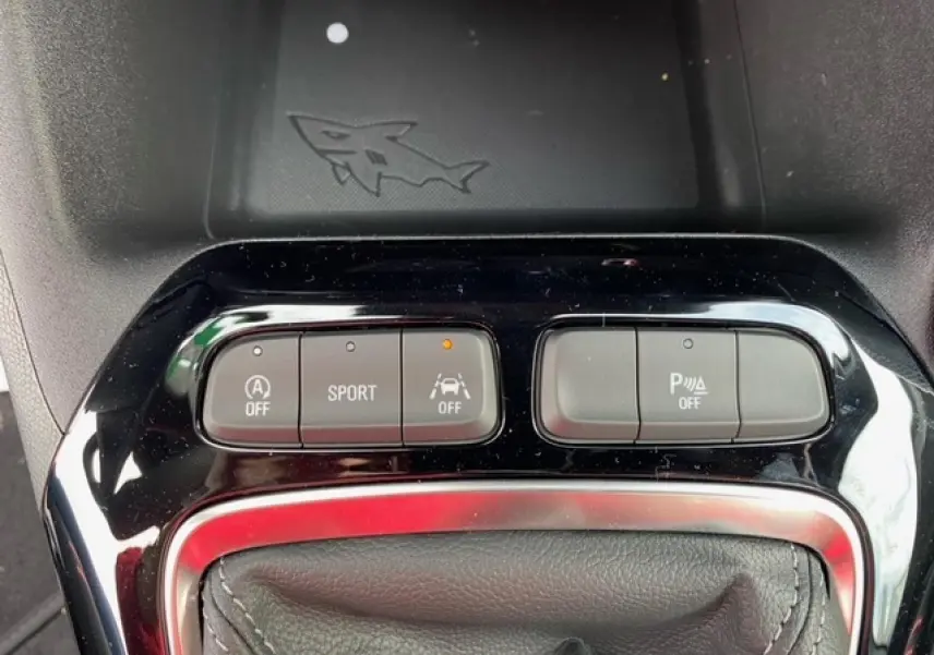 Gros plan sur la console centrale de l'Opel Corsa gris magnetic, montrant les boutons de contrôle du mode sport et aides à la conduite.