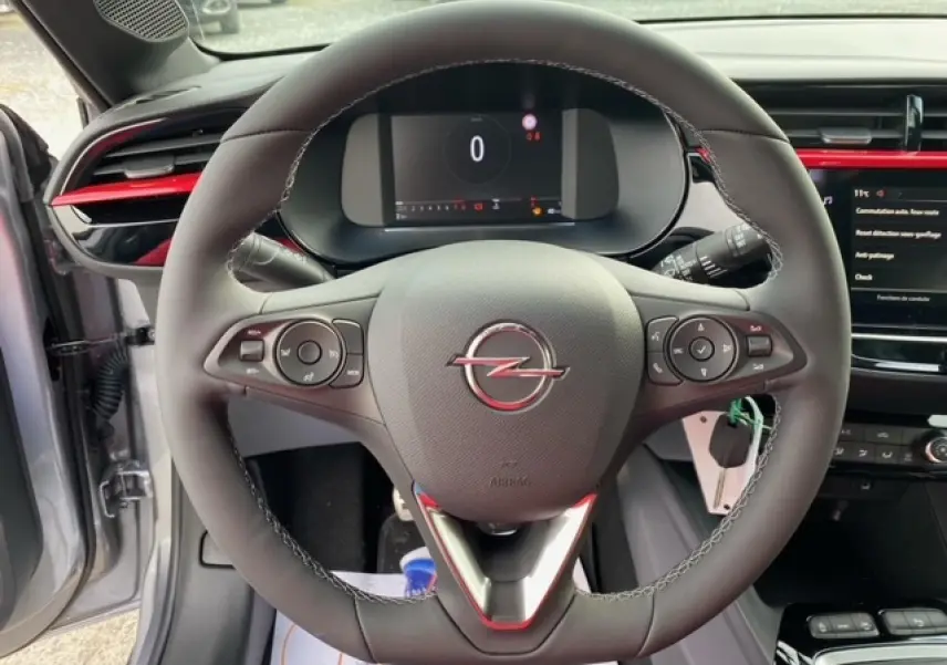 Vue rapprochée du volant noir de l'Opel Corsa 2022 gris magnetic, avec tableau de bord numérique et insert rouge.