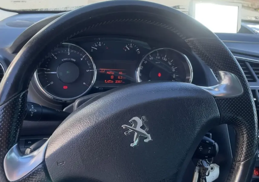 Vue intérieure centrée sur le volant noir d'une Peugeot 3008 2016 avec tableau de bord et clés insérées.