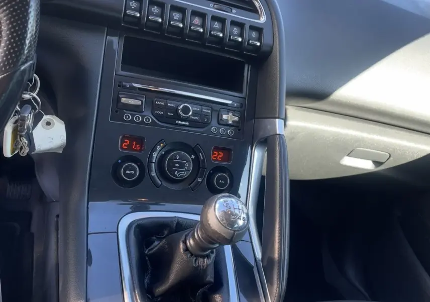 Intérieur de Peugeot 3008 noir, vue rapprochée sur la console centrale avec levier de vitesse manuel et commandes climatisation.