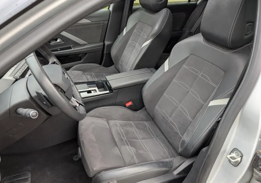 Vue intérieure côté conducteur de l'Opel Astra 2024 avec sièges mixte Alcantara et cuir gris foncé et console centrale noire.