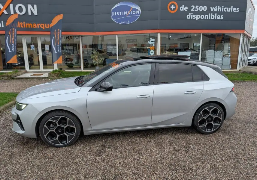 Opel Astra 2024 gris métallisé vue de profil côté gauche avec jantes alliage noires et toit noir panoramique.