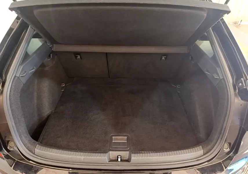 Coffre ouvert vu de l'arrière d'un Volkswagen Taigo noir 2023, espace de chargement vide et tapis noir.