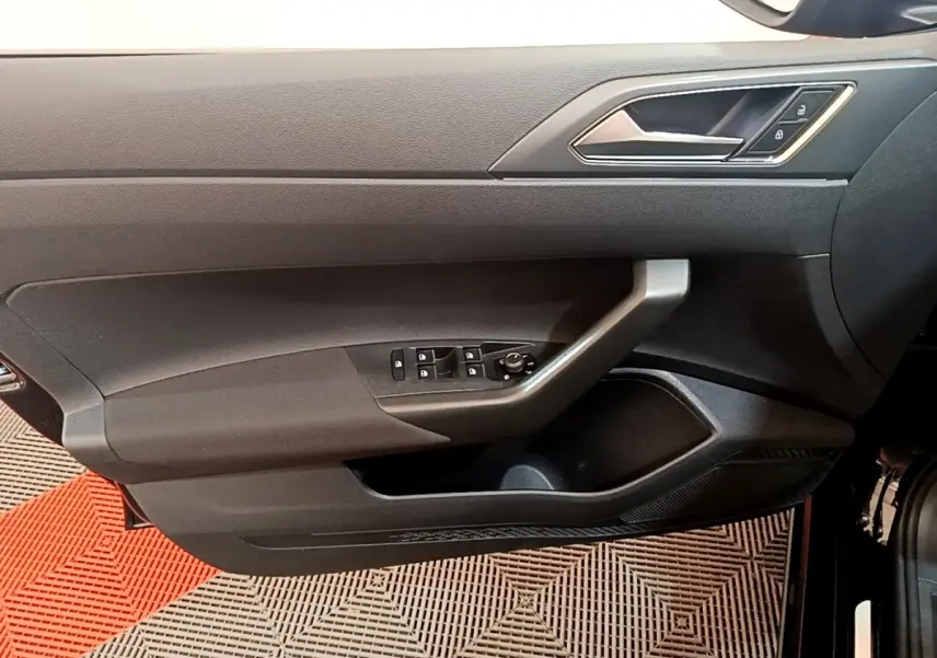 Vue côté gauche de la porte intérieure noire du Volkswagen Taigo 2023 avec commandes de vitres et verrouillage.