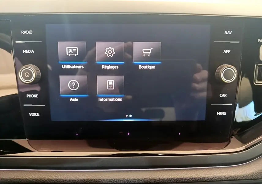 Écran tactile central du tableau de bord du Volkswagen Taigo noir, affichant le menu principal avec options utilisateurs, réglages et boutique.