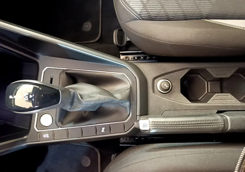 Vue rapprochée de la console centrale du Volkswagen Taigo noir 2023, avec levier de vitesse automatique et frein à main.