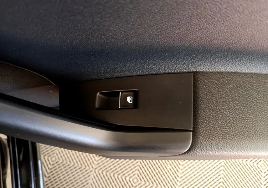 Gros plan sur le bouton de verrouillage des portes côté conducteur d’un Volkswagen Taigo noir 2023.