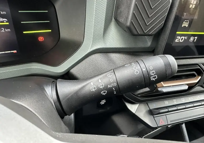 Vue rapprochée du commodo d’essuie-glace noir dans l’habitacle du Dacia Duster blanc Glacier 2025.