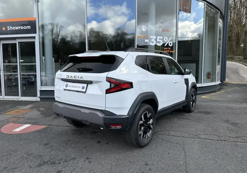 Vue 3/4 arrière droite du Dacia Duster blanc glacier avec jantes alliage noires et vitres surteintées.