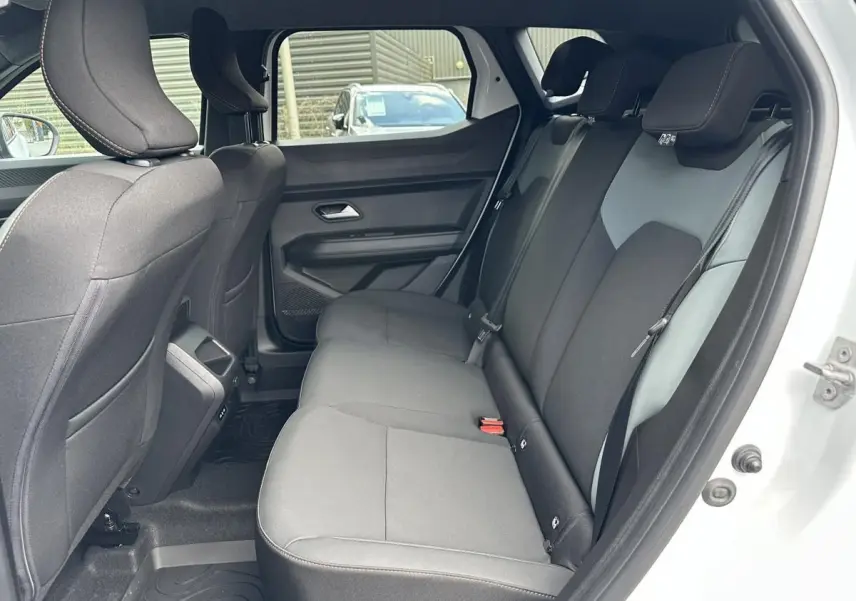 Vue intérieure côté droit sur la banquette arrière noire du Dacia Duster blanc glacier 2025, porte ouverte.