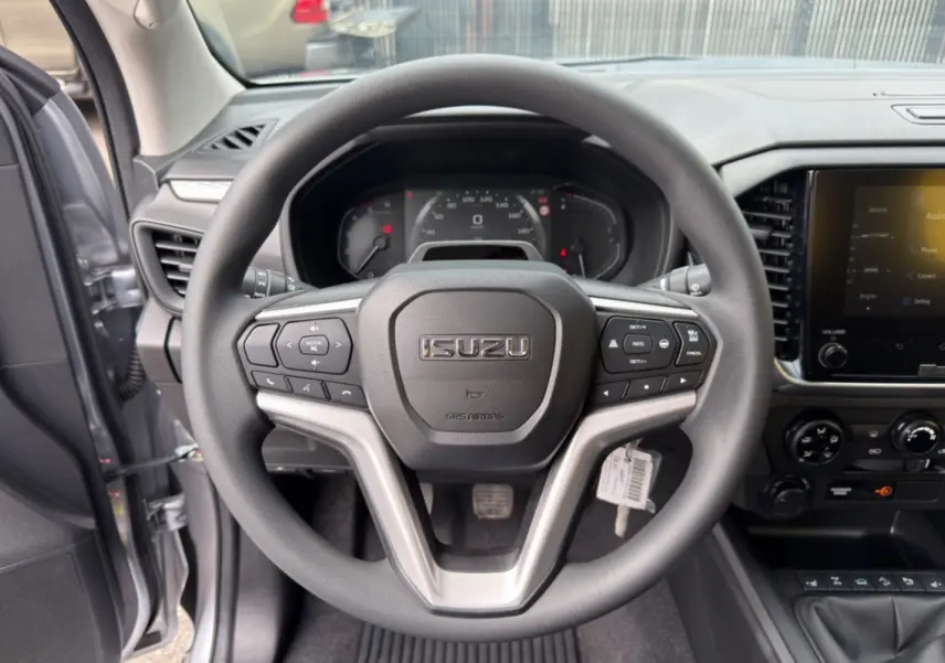 Vue intérieure centrée sur le volant multifonctions noir d’un Isuzu D-MAX 2026 avec tableau de bord et écran tactile.