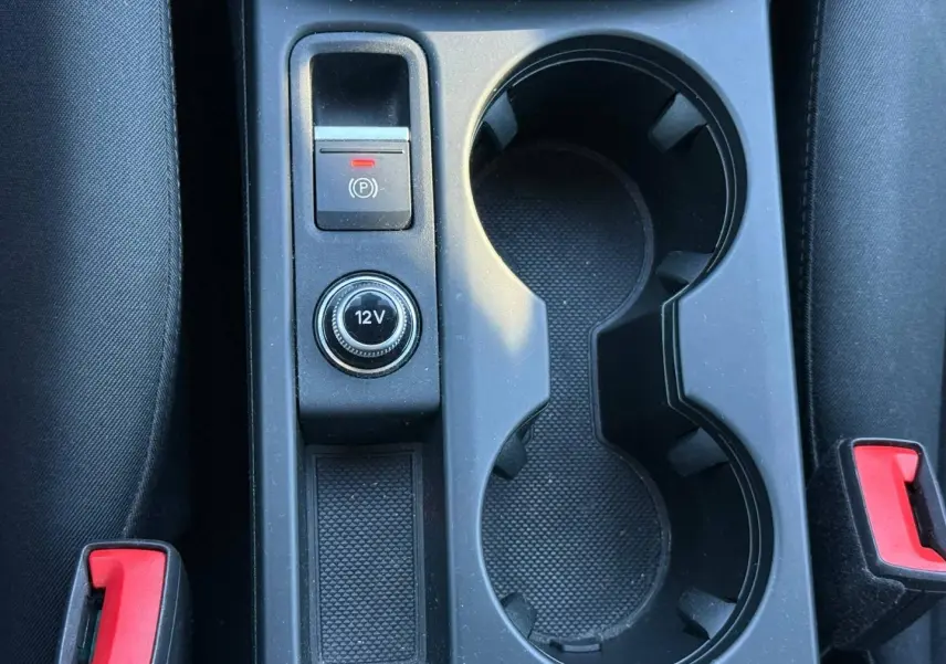 Gros plan sur la console centrale noire de l’Audi A3 Sportback 2024, avec porte-gobelets et bouton 12V visible.