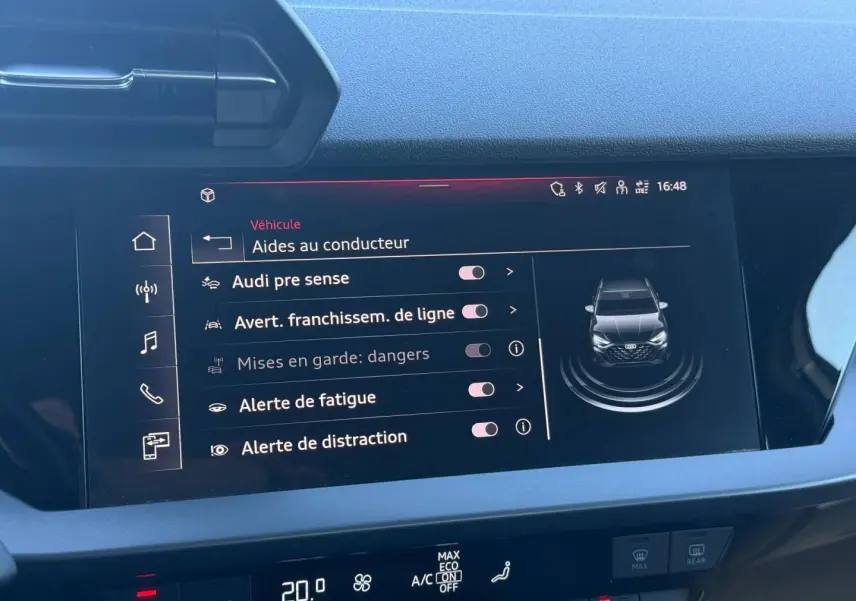 Écran tactile intérieur affichant les aides à la conduite d'une Audi A3 Sportback blanche, vue de face sur l'écran.