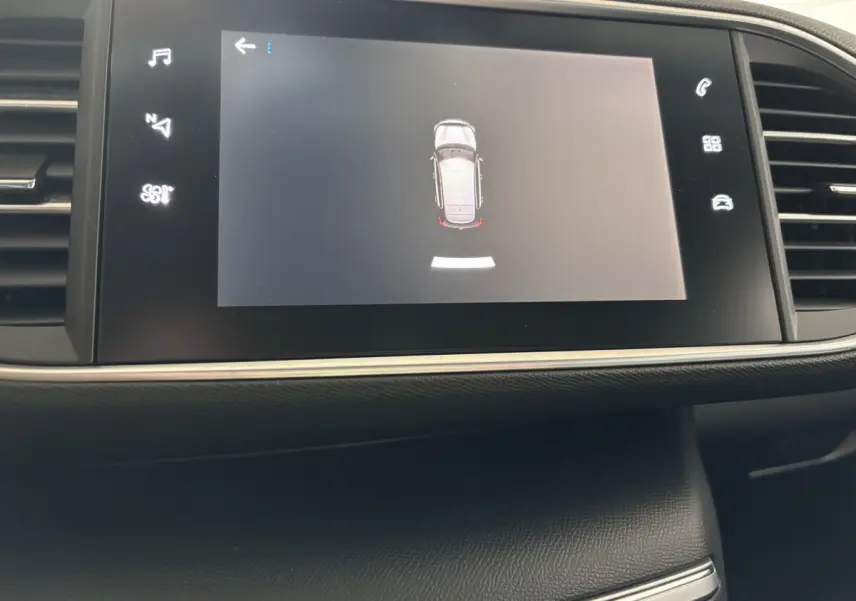 Écran tactile central de la Peugeot 308 gris foncé affichant l'aide au stationnement en vue aérienne.