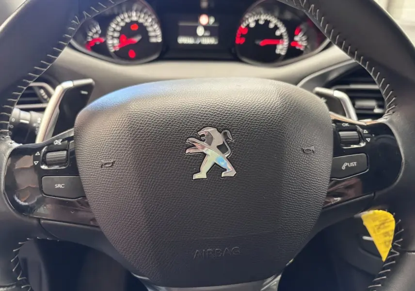 Volant en cuir noir de Peugeot 308 Puretech 2019 avec commandes intégrées et logo lion au centre, vue rapprochée frontale.