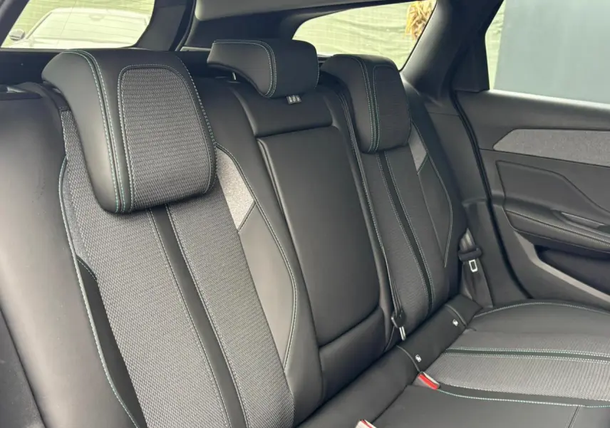 Vue intérieure des sièges arrière noirs avec surpiqûres bleues du Peugeot 308 SW Hybrid 2025 côté droit.