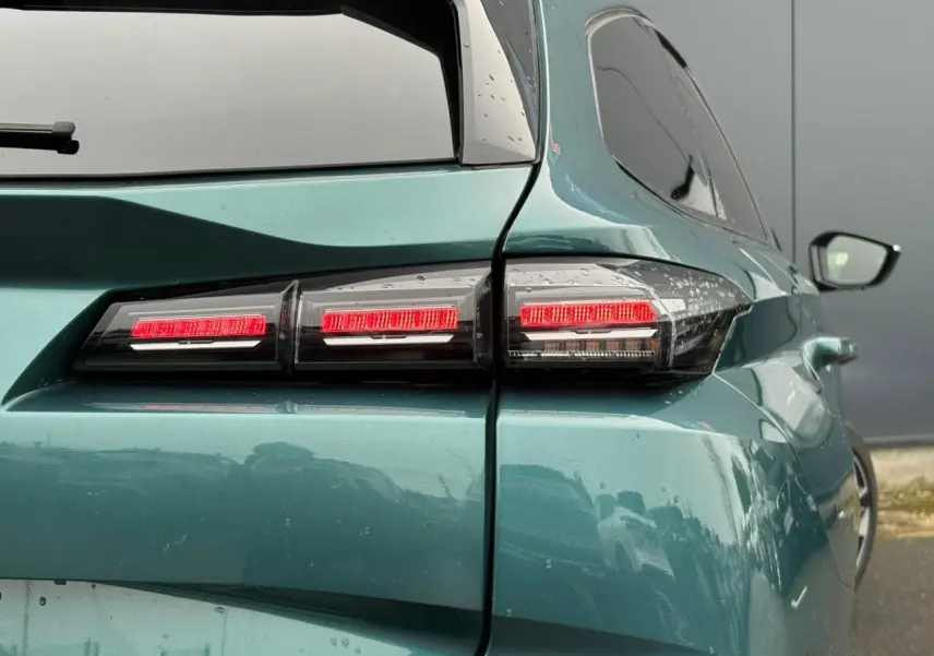 Feu arrière droit allumé d'une Peugeot 308 SW Hybrid 2025 bleu cuivre, vue en léger 3/4 arrière droit.