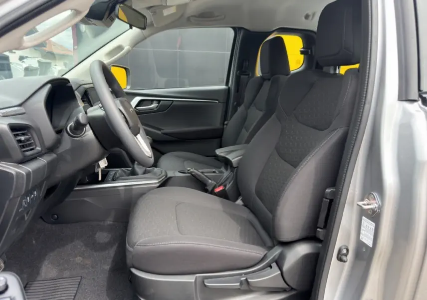 Vue intérieure côté conducteur du pick-up Isuzu D-MAX 2.2 TD 164 Space Evolution, sièges tissu gris et accoudoir central.