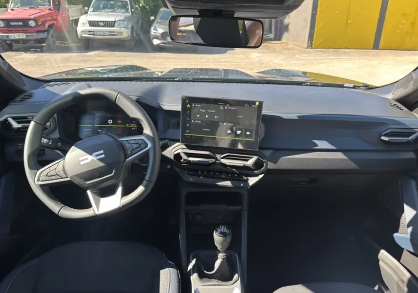 Vue intérieure avant du Dacia Bigster TCE 130 4x4 vert cèdre, avec tableau de bord moderne et écran tactile central.