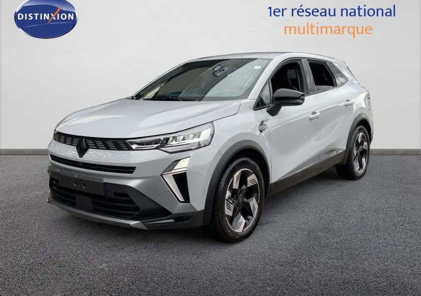 Renault Symbioz gris Rafale métal en 3/4 avant droit, SUV hybride avec phares LED et jantes bicolores distinctives.