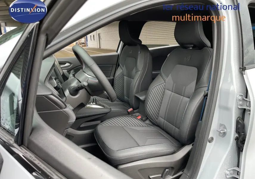 Vue intérieure côté conducteur du Renault Symbioz gris Rafale Métal, mettant en valeur les sièges en tissu et cuir avec surpiqûres bleues.