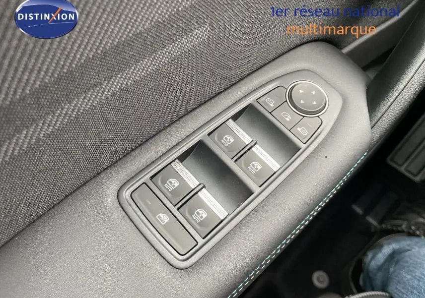 Gros plan sur les commandes des vitres électriques côté gauche d’un Renault Symbioz gris Rafale Métal, intérieur noir avec surpiqûres bleues.