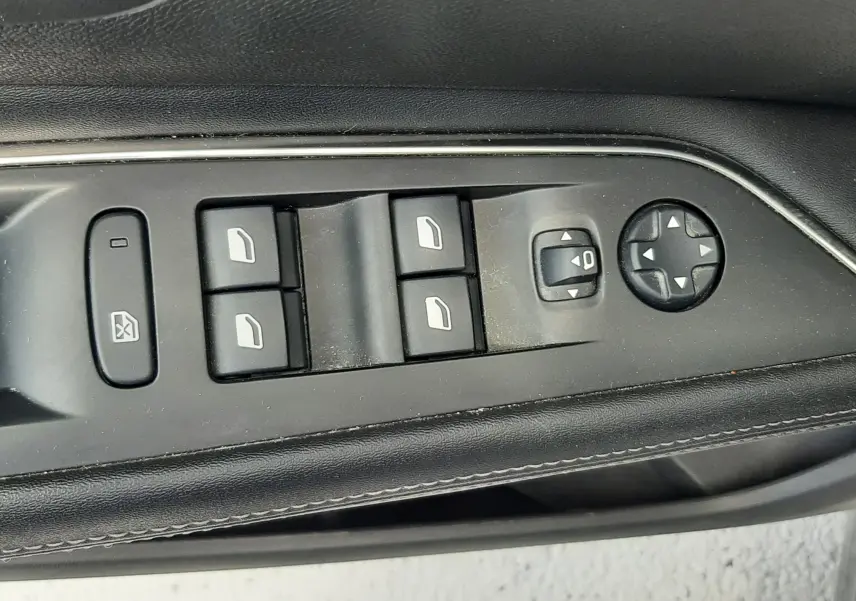 Gros plan sur les commandes de lève-vitres et réglage des rétroviseurs côté conducteur d'un Peugeot 3008 gris 2020.