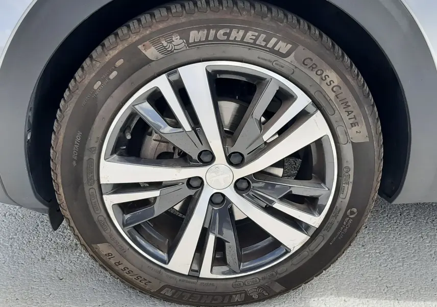 Gros plan sur la jante alliage bicolore et pneu Michelin CrossClimate 2 du côté avant droit d'un Peugeot 3008 gris.