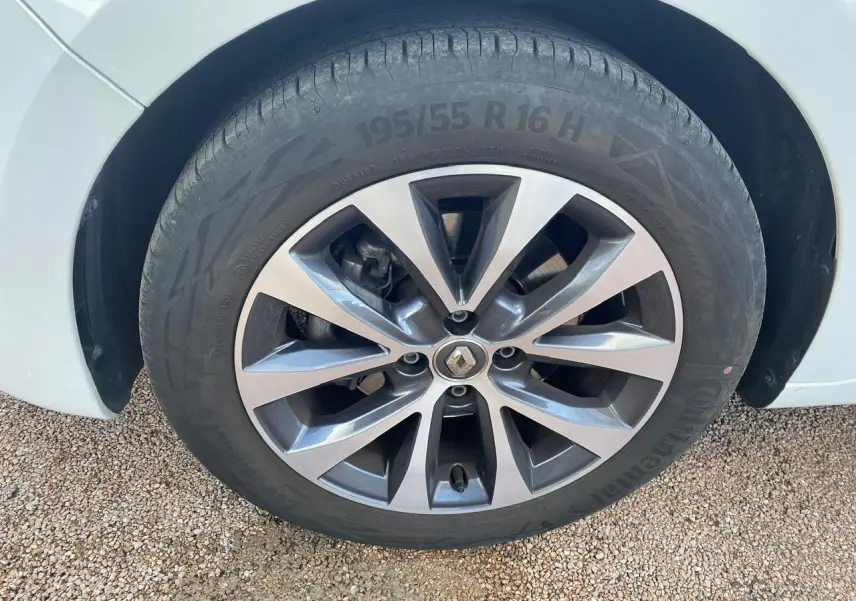 Gros plan sur la roue avant gauche d'une Renault Clio blanche avec jante alliage à dix branches.