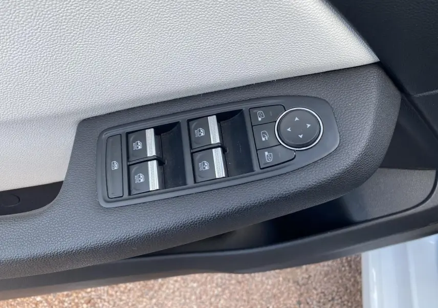 Commande des vitres électriques et réglage des rétroviseurs sur la porte côté gauche d'une Renault Clio blanche 2021.