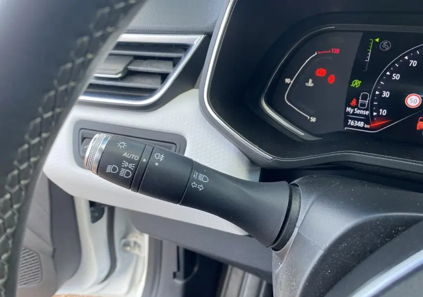 Gros plan sur la commande des phares et clignotants à gauche du volant dans une Renault Clio blanche de 2021.
