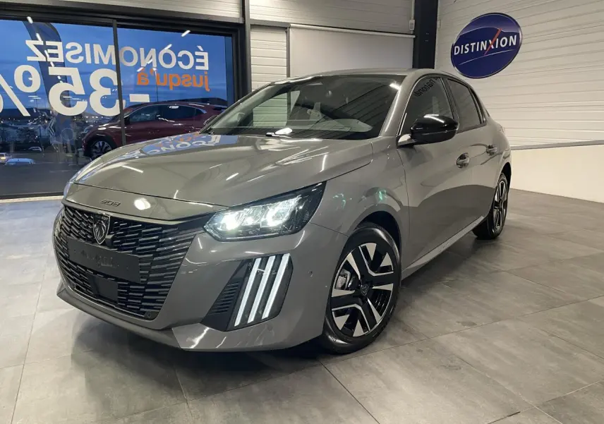 Peugeot 208 gris selenium vue 3/4 avant en intérieur, avec phares LED et jantes alliage bi-ton distinctives.