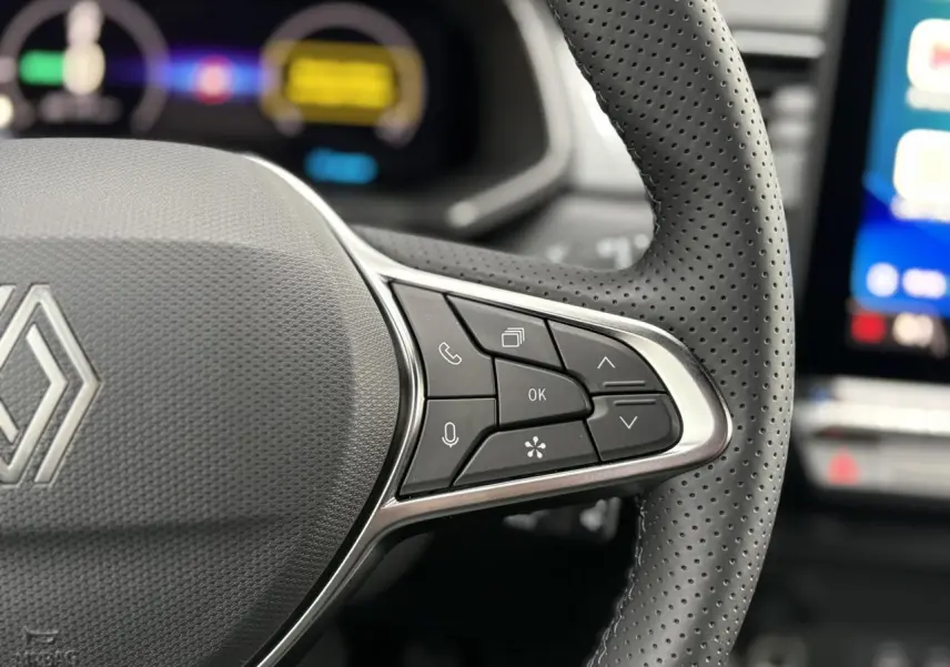 Gros plan sur le volant en cuir perforé du Renault Captur noir étoile, avec commandes multifonctions visibles.