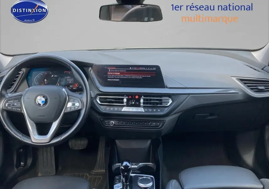 Tableau de bord et volant multifonction de BMW Série 1 gris foncé, vue frontale intérieure avec écran central allumé.