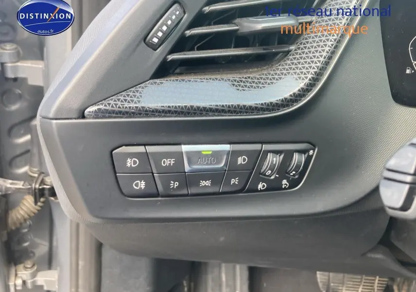 Détail des commandes d'éclairage intérieures sur la gauche du tableau de bord de la BMW Série 1 gris foncé 2023.