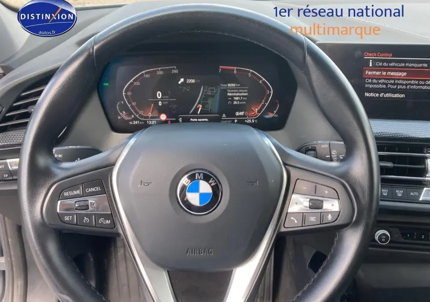 Volant sport en cuir noir de BMW Série 1 118i 2023 vu de face avec tableau de bord digital allumé