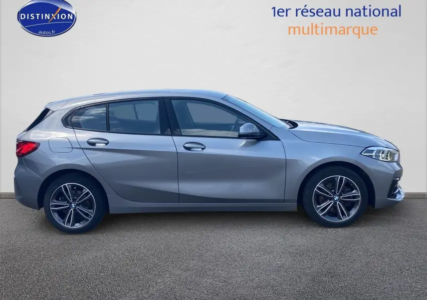 Profil côté gauche d'une BMW Série 1 gris foncé 2023 avec jantes alliage 17 pouces et lignes sportives marquées.