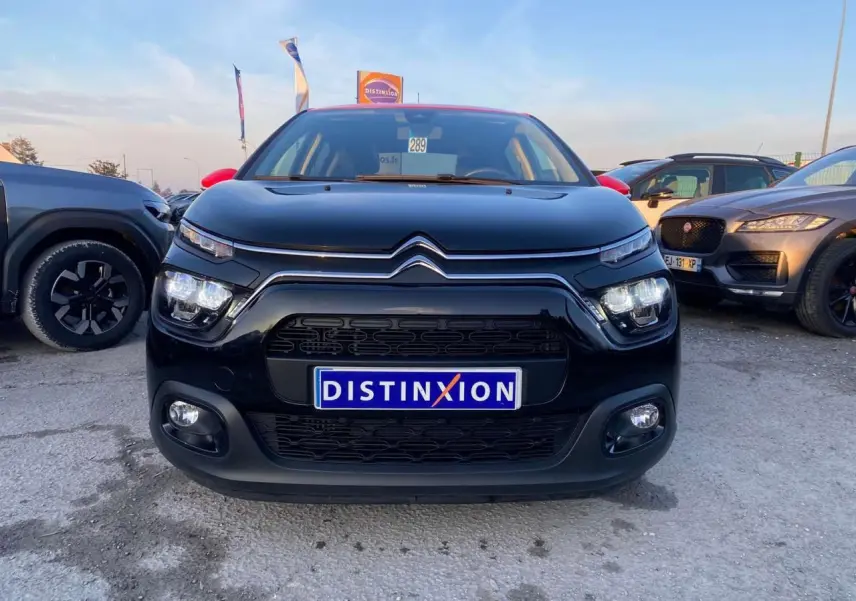 Vue frontale d'une Citroën C3 Shine 2023 noire avec toit rouge et projecteurs LED allumés.