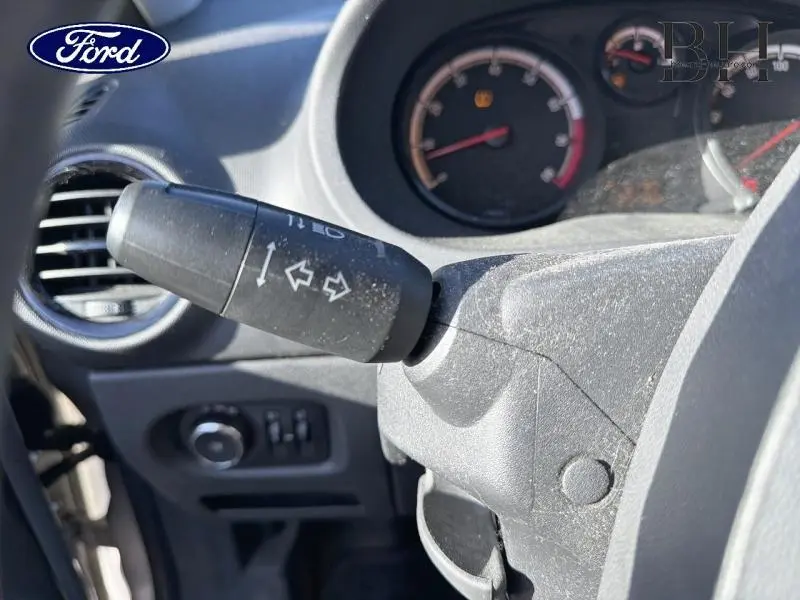 Gros plan sur le commodo gauche avec les clignotants d'une Opel Corsa gris minéral, tableau de bord en arrière-plan flou.