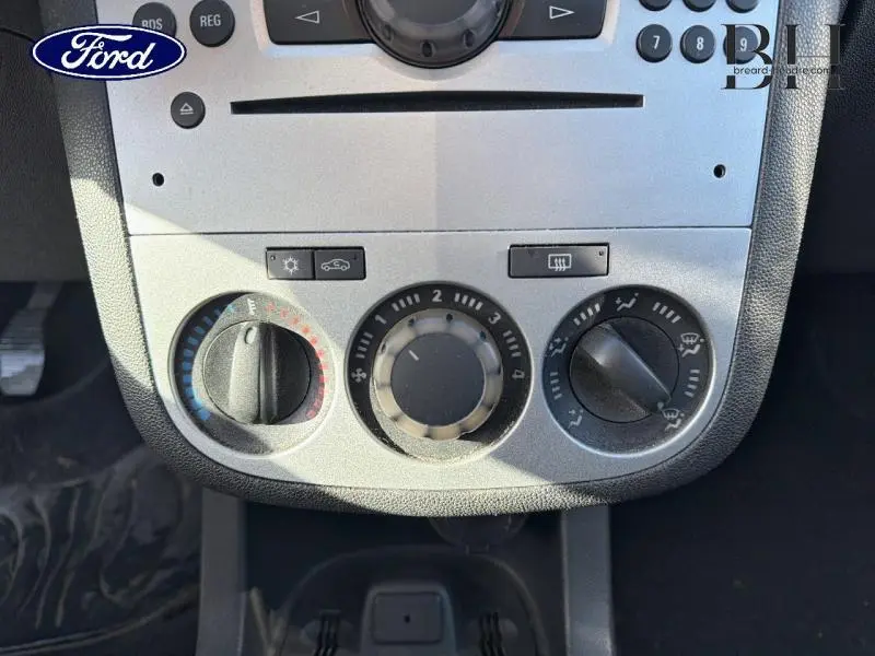 Gros plan sur la console centrale grise de l'Opel Corsa 2014 montrant les commandes de climatisation et ventilation.